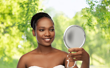 Image showing smiling african american woman looking to mirror