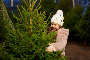 Image showing little girl choosing christmas tree at market