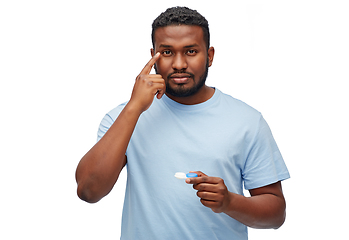 Image showing young african american man applying contact lenses