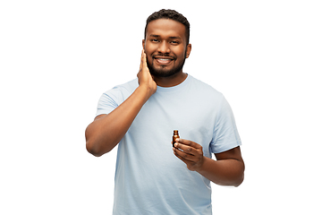 Image showing african man applying grooming oil to beard