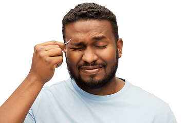 Image showing african man with tweezers tweezing his eyebrow