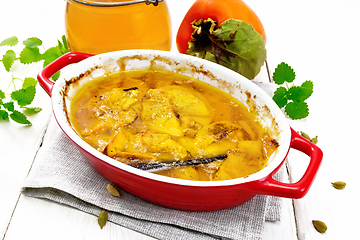 Image showing Persimmons baked with honey in pan on wooden board