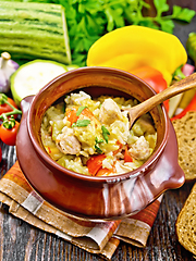 Image showing Rice with chicken and vegetables in pot on brown board