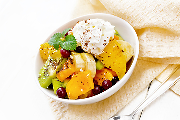 Image showing Salad fruit with cranberries and cream in bowl on light board