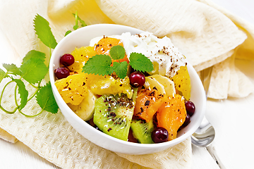 Image showing Salad fruit with cranberries and cream in bowl on wooden board