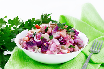 Image showing Salad with herring and beetroot in bowl on wooden board