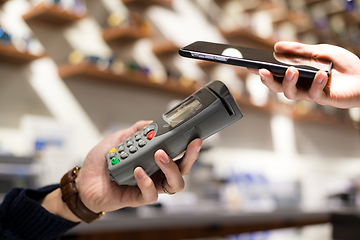 Image showing Woman paying with NFC technology on mobile phone in shop