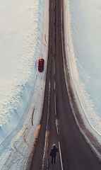 Image showing Surreal image with an unusual perspective with a woman on a winter road and car