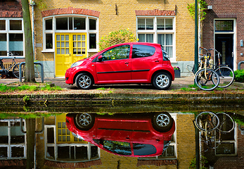 Image showing Red car on canal embankment in street of Delft. Delft, Netherlands