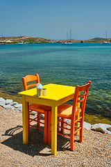 Image showing Cafe tableon beach in Adamantas town on Milos island with Aegean sea with boats in background