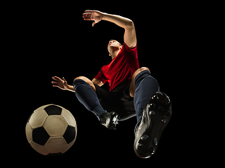 Image showing Young caucasian football, soccer player in action, motion isolated on black background, look from the bottom. Concept of sport, movement, energy and dynamic.