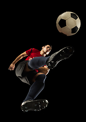 Image showing Young caucasian football, soccer player in action, motion isolated on black background, look from the bottom. Concept of sport, movement, energy and dynamic.