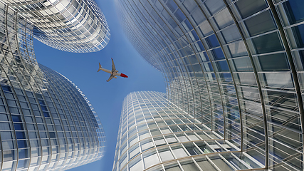 Image showing Plane flying over modern office glass skyscrapers