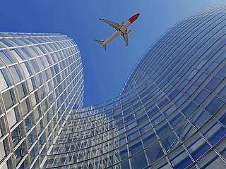 Image showing Plane flying over modern office glass skyscrapers