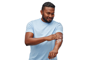 Image showing happy african man applying moisturizer to his hand