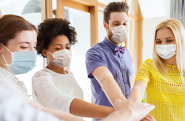 Image showing people in masks stacking hands at office