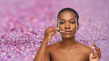 Image showing african american woman applying lip gloss