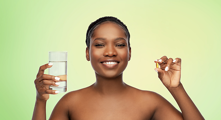 Image showing african woman with cod liver oil and water glass