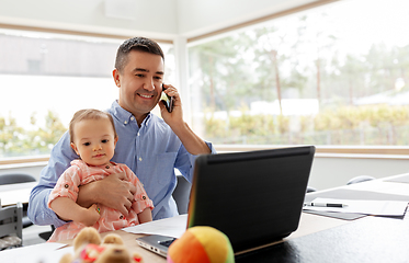 Image showing father with baby calling on phone at home office