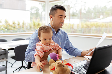 Image showing father with baby and papers working at home office