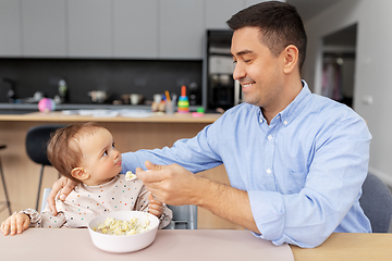 Image showing happy father feeding baby in highchair at home