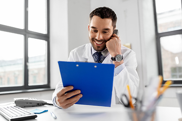 Image showing male doctor calling on desk phone at hospital