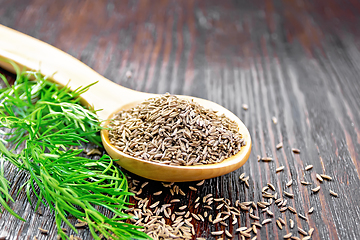 Image showing Cumin seeds in spoon with herbs on wooden table