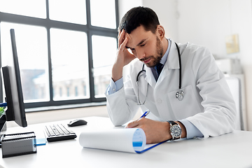 Image showing stressed male doctor with clipboard at hospital