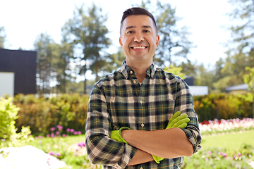 Image showing happy smiling middle-aged man in gloves at garden