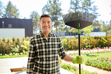 Image showing happy middle-aged man with leaf rake at garden