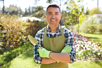 Image showing happy man in apron with trowel at summer garden