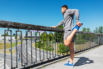 Image showing man stretching leg on bridge