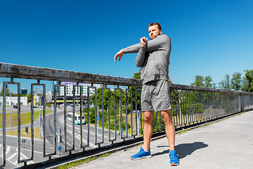 Image showing man stretching hand and shoulder on bridge