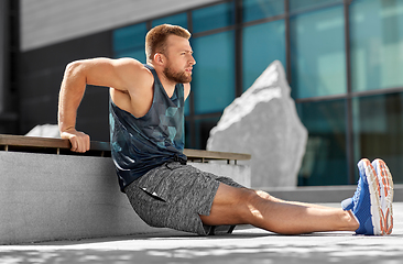 Image showing young man doing triceps dip on city street