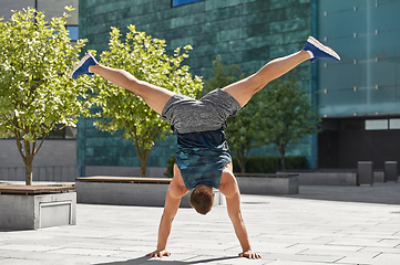 Image showing young man exercising and doing handstand outdoors