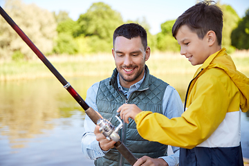 Image showing happy smiling father and son fishing on river