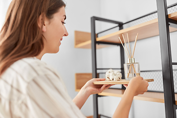 Image showing woman placing aroma reed diffuser to shelf home