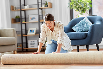 Image showing young woman unfolding carpet at home