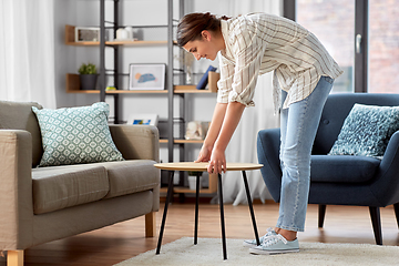 Image showing woman placing coffee table next to sofa at home