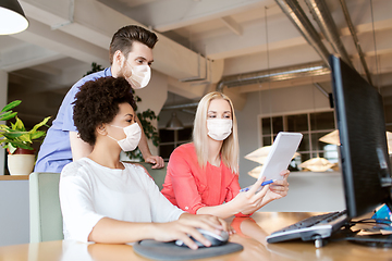 Image showing creative team in masks with computer in office