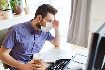 Image showing office worker in mask with computer and coffee