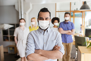 Image showing young man in mask over creative team in office