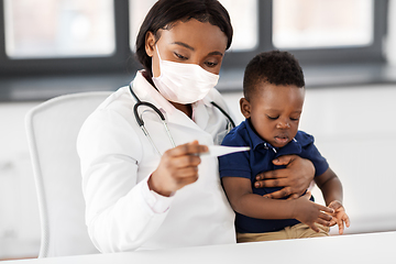 Image showing doctor in mask measuring baby's temperature