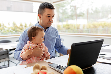 Image showing father with baby working on laptop at home office