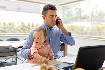 Image showing father with baby calling on phone at home office