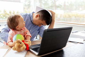 Image showing father with baby working on laptop at home office