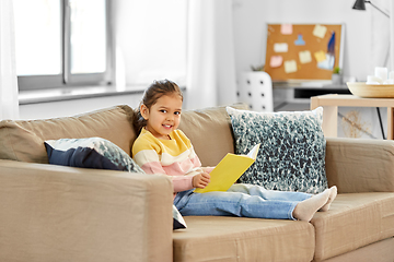 Image showing happy smiling little girl reading book at home