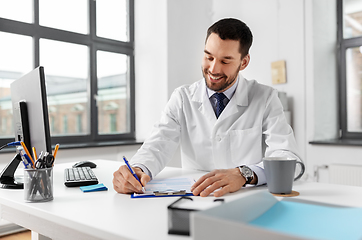 Image showing smiling male doctor with clipboard at hospital