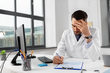 Image showing stressed male doctor with clipboard at hospital