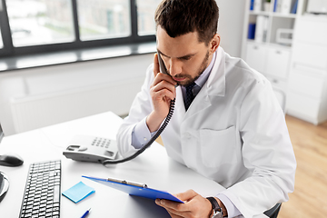 Image showing male doctor calling on desk phone at hospital